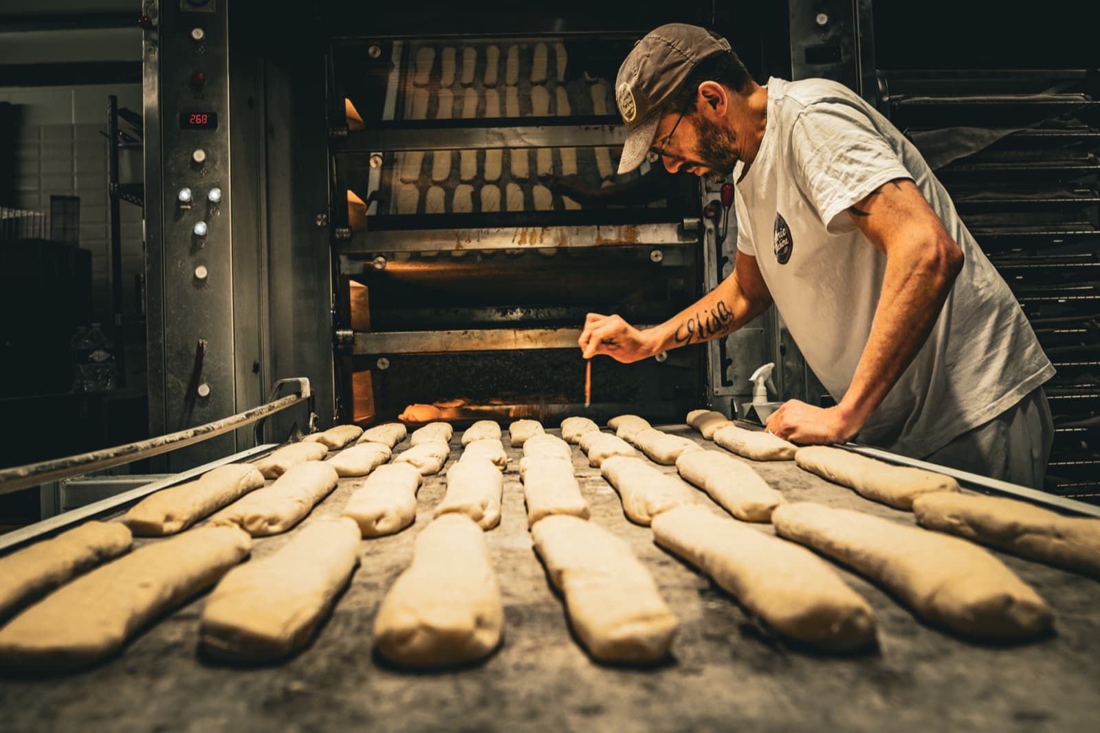 Boulanger Marie Blachère scarifiant les baguettes crues devant le four à sole